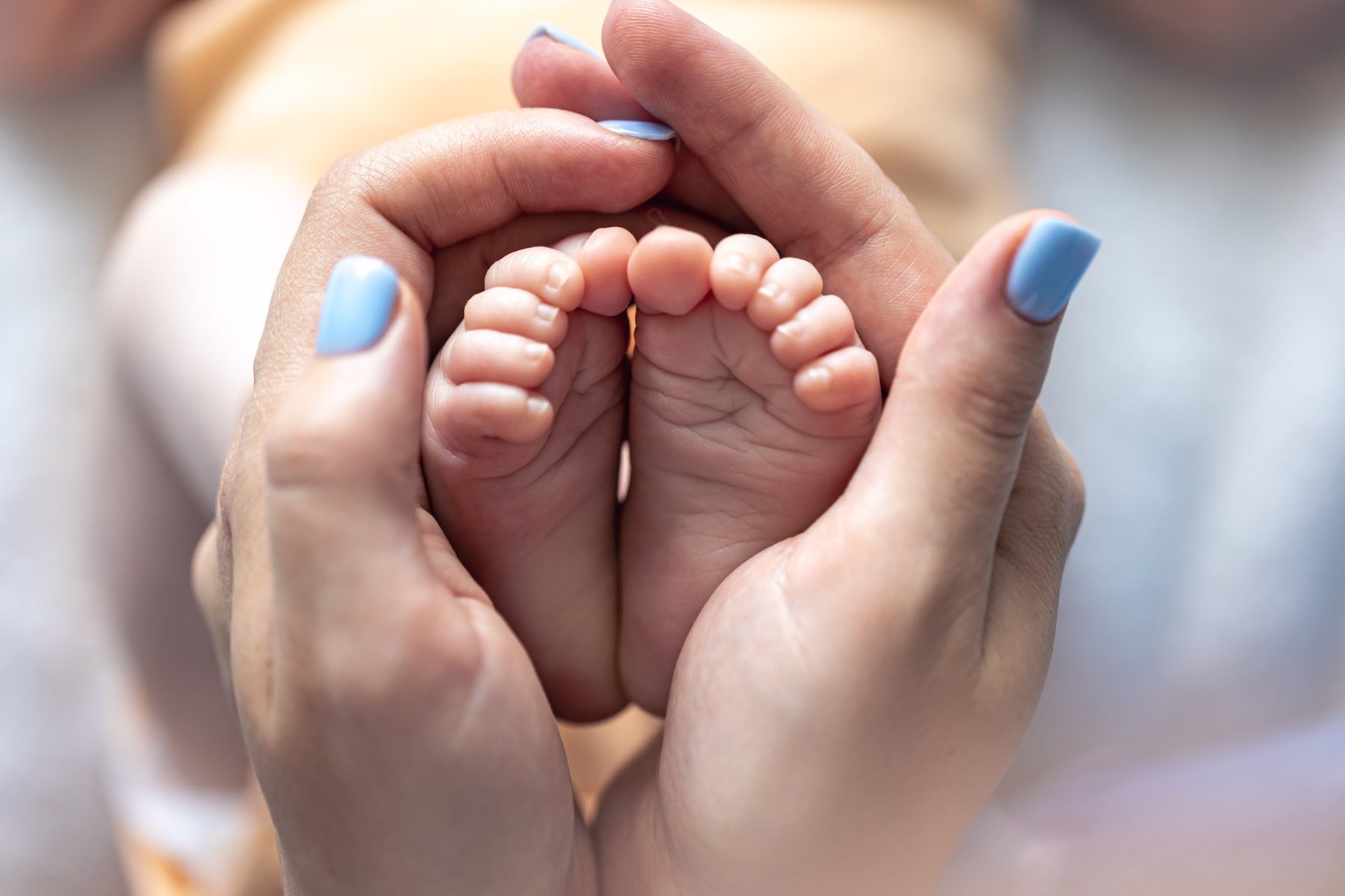 Manos de mamá sosteniendo los pies de su bebé